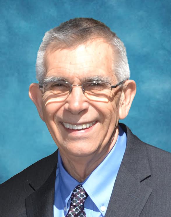 Portrait of a smiling man in a suit and tie against a blue background