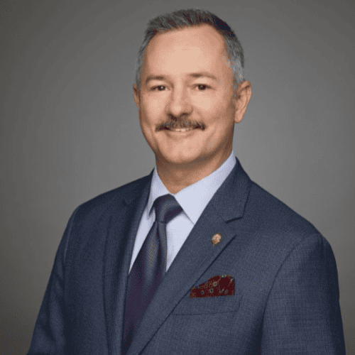 Portrait of a man in a suit and tie against a gray background