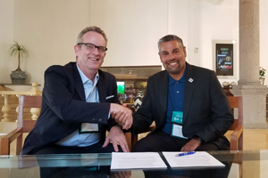 two males in business casual clothing shake hand and smile for a photo