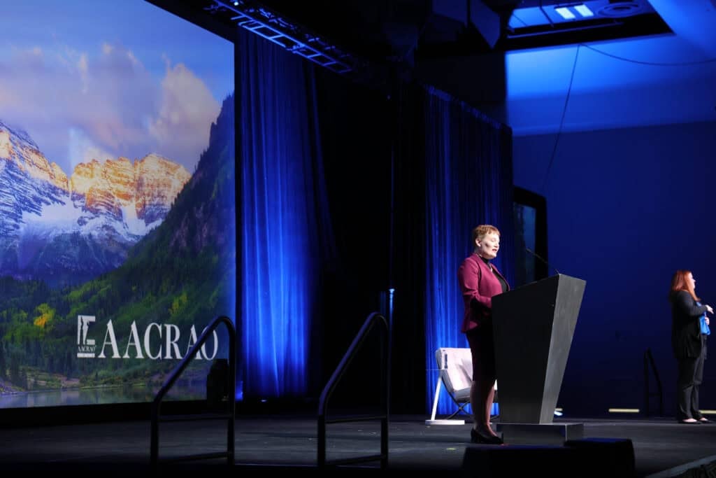 Speaker at a podium on the AACRAO conference main stage
