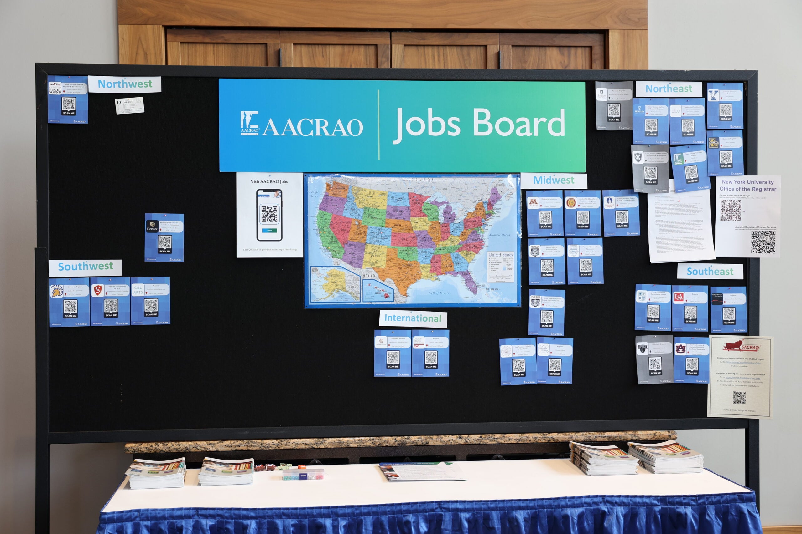 
The AACRAO Jobs Board displayed at a conference, with job postings organized by region on a bulletin board.