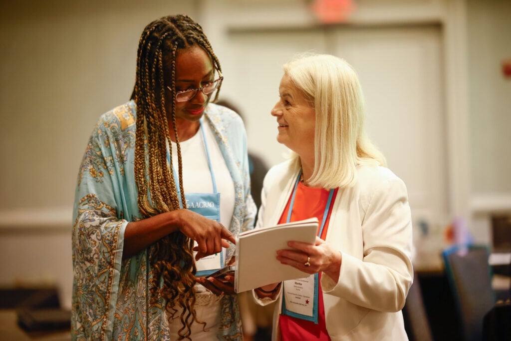 Two AACRAO conference attendees conversing and reviewing materials together.