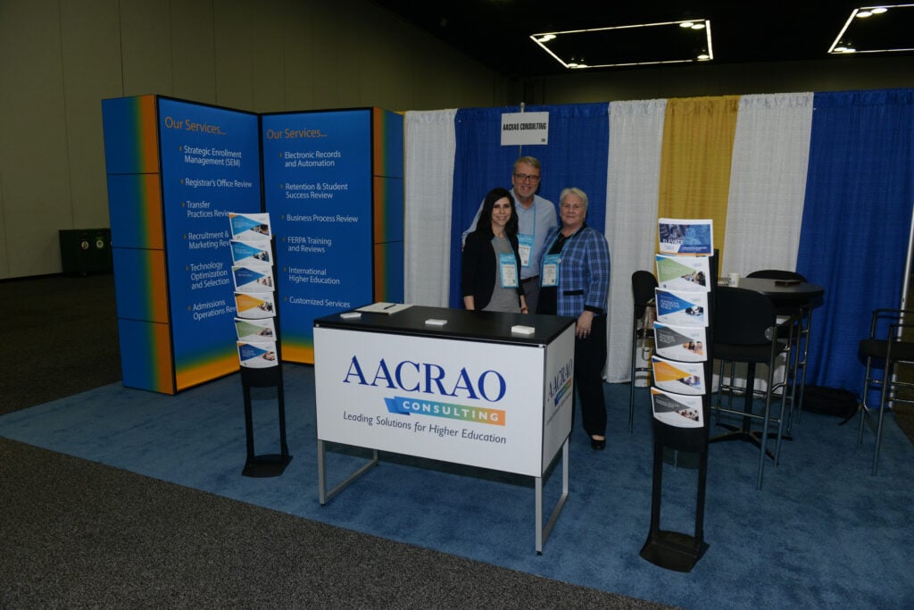 AACRAO Consulting booth at a conference with three staff members standing behind a table