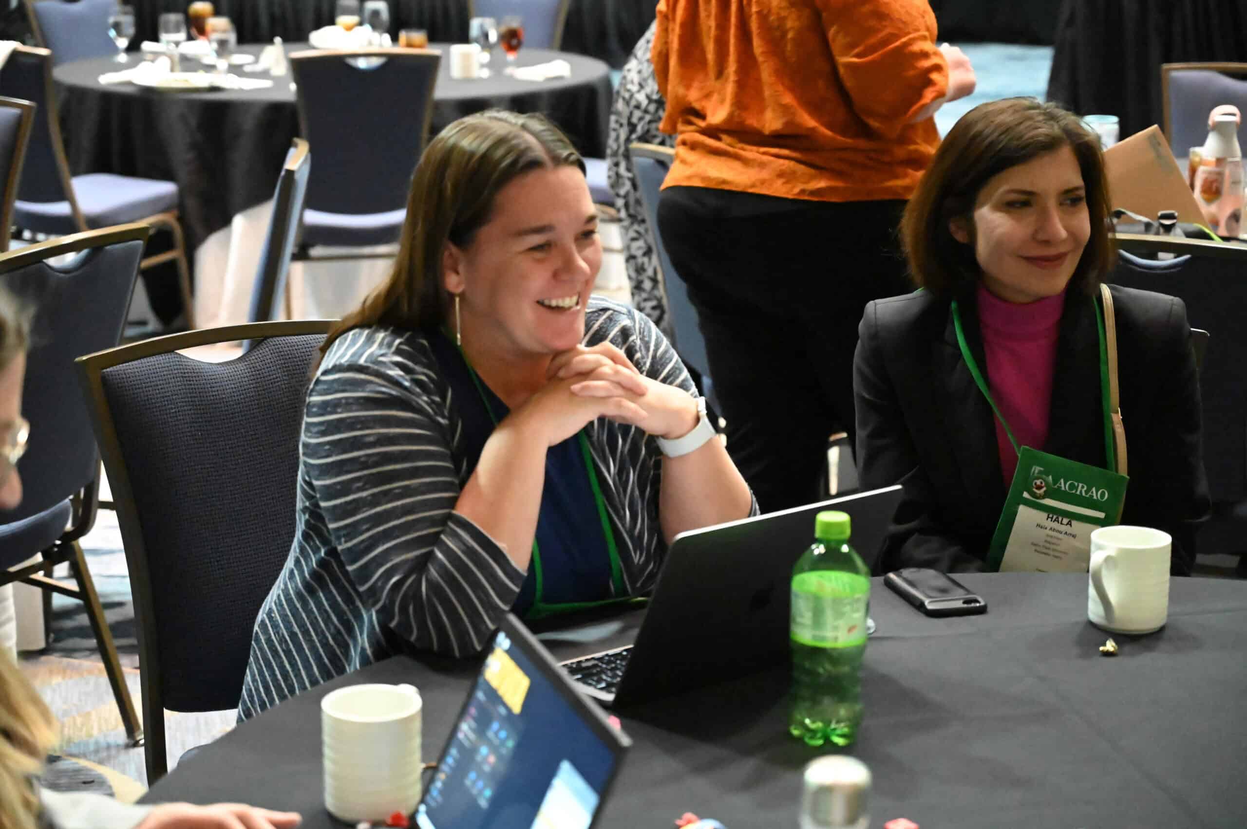 Two attendees sat at a working table, smiling during an AACRAO conference session