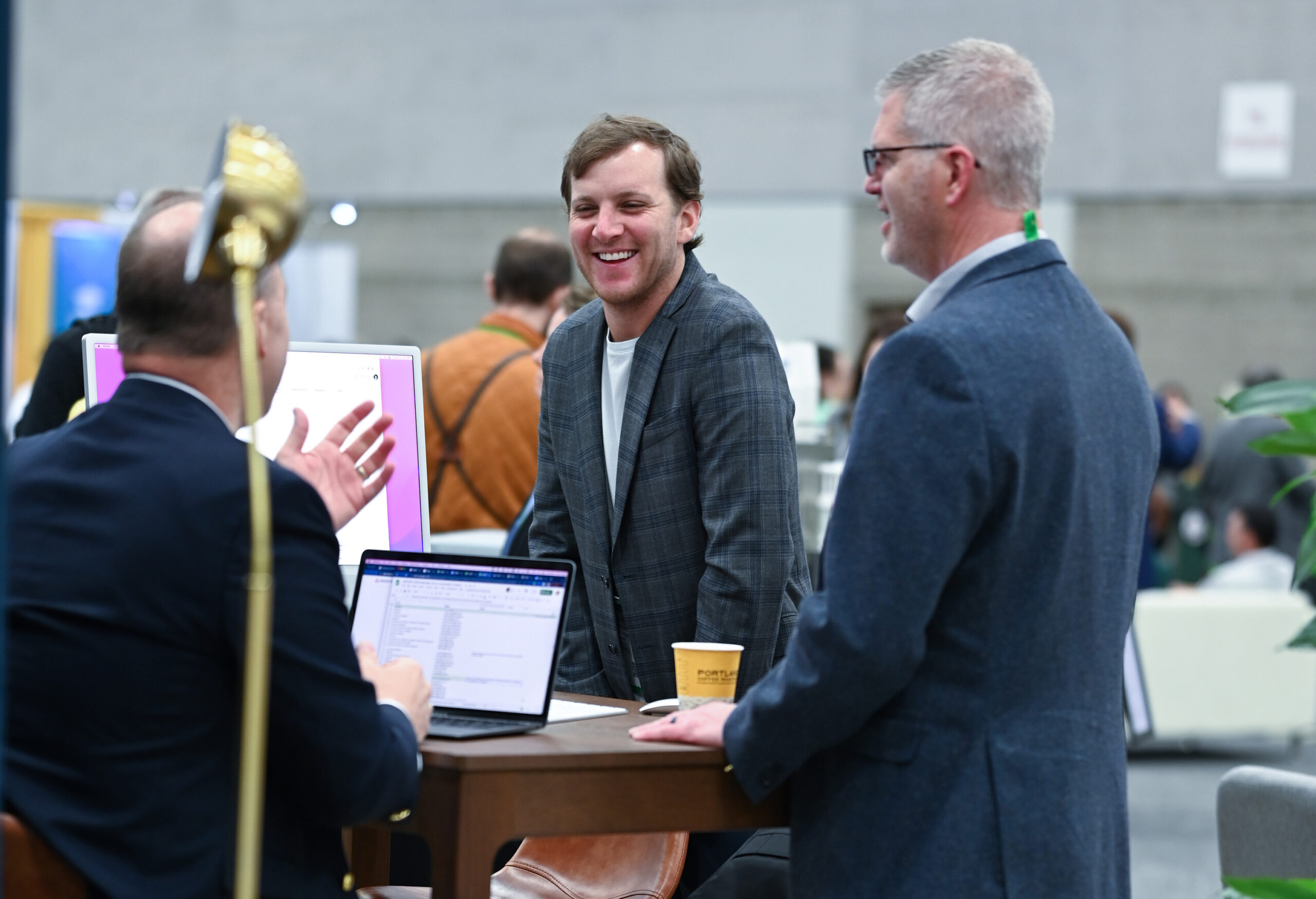 Professionals networking and discussing at an AACRAO event table with laptops and materials