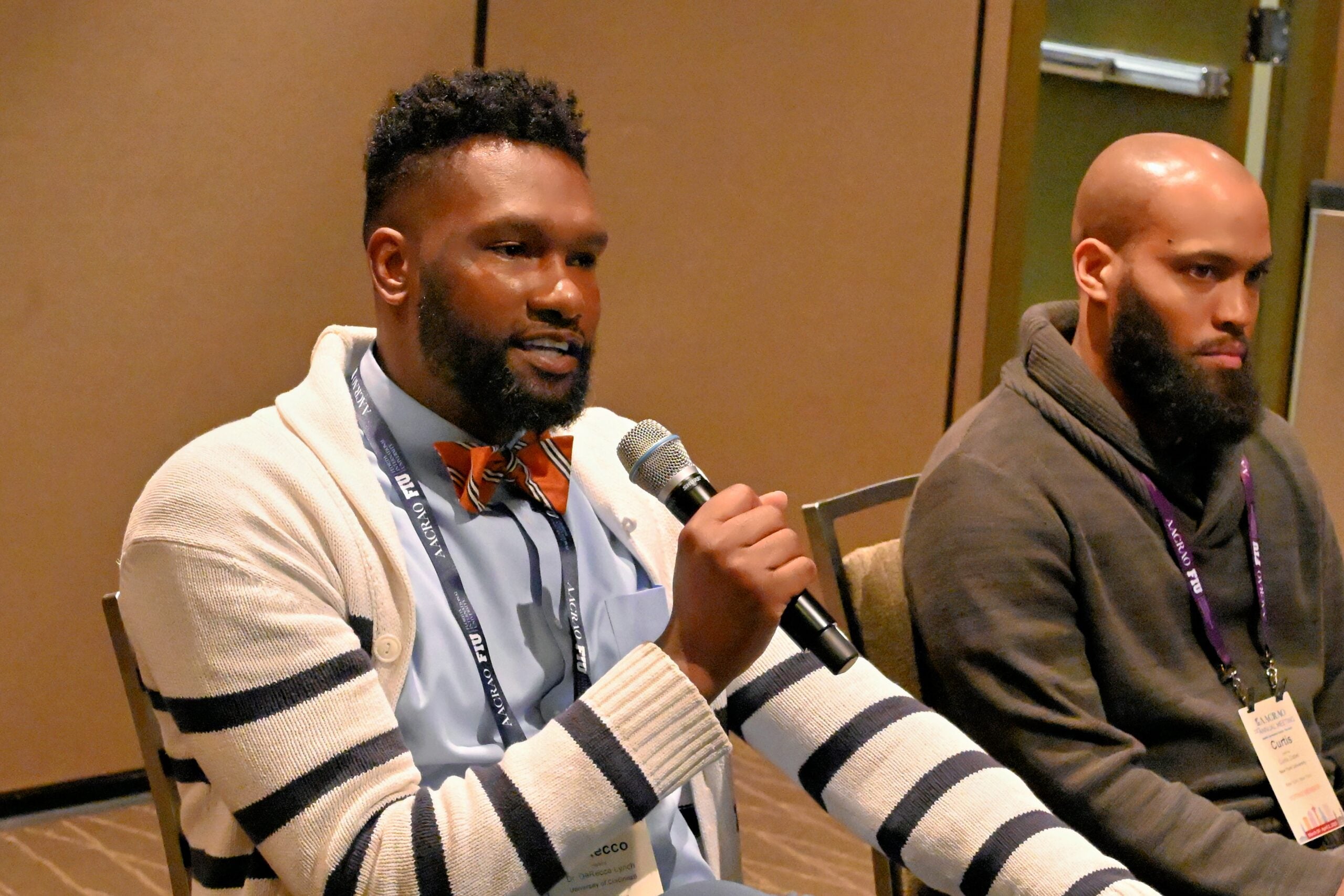 Two conference attendees speaking at a panel while holding microphones