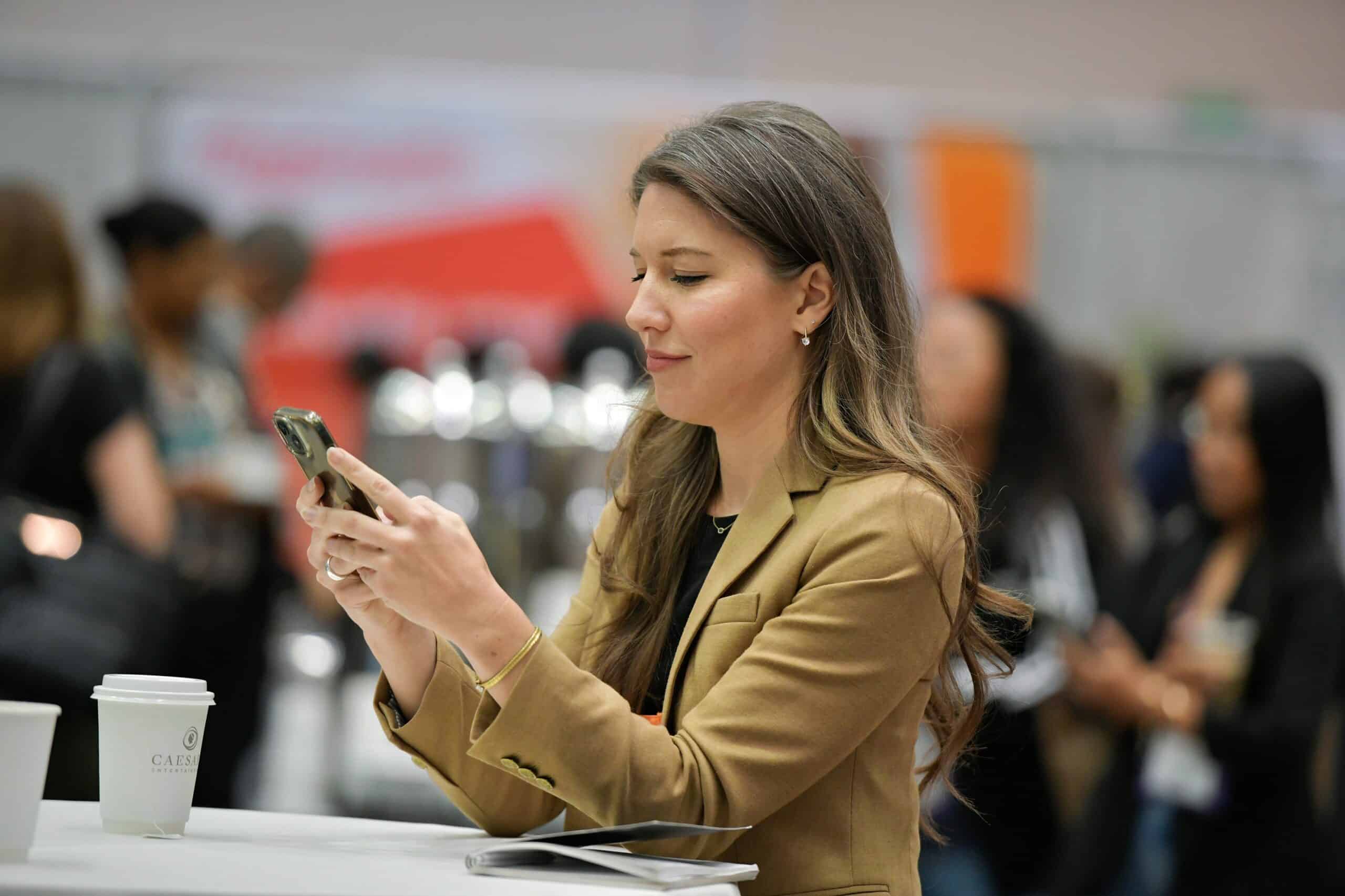 Attendee checking her phone on the conference expo floor
