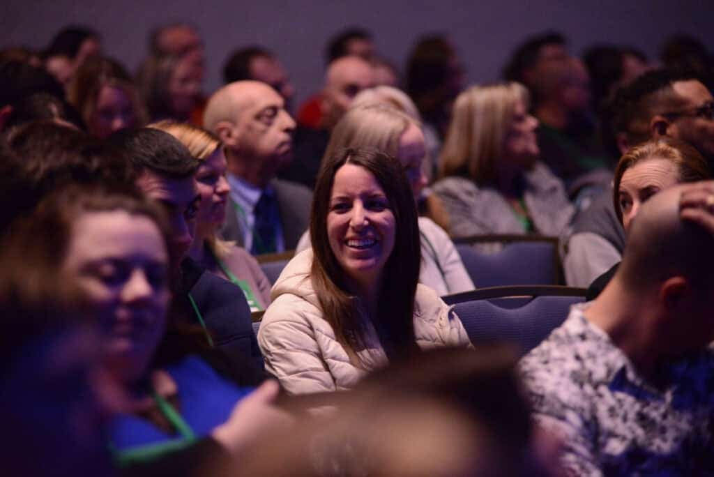 Smiling attendee in a crowd at a conference session