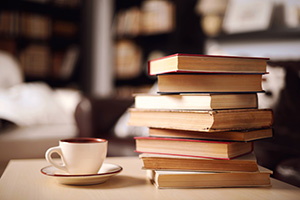 Stack of books with a coffee cup on a table in a library setting