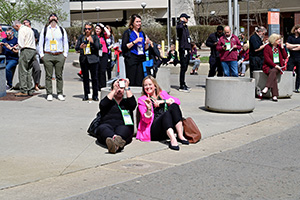People kneeling and posing for a group photo outdoors on a city sidewalk