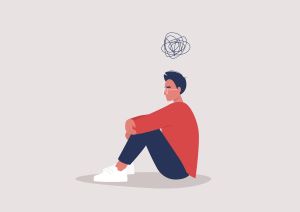 worried student sits with arms crossed around knees