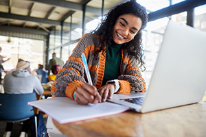 Person smiling while working on a laptop at a cafe or coworking space