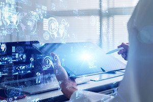person working on a tablet as various translucent graphs and images float above the screen