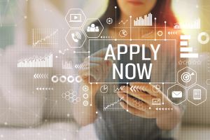 "Apply Now" with woman using a smartphone