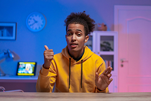 Young student recording a video of himself.