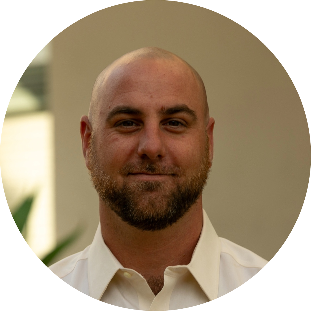 Portrait of a man with a shaved head and beard wearing a white shirt