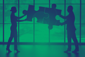 Two people holding puzzle pieces together