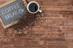 wooden table with a mug of coffee, spilled coffee beans, and a blackboard with the words "coffee break" displayed