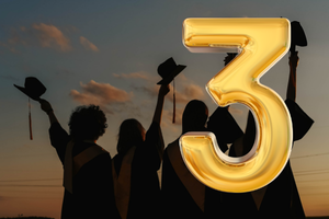 Graduates raising their caps at dusk with the number 3