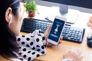 female wearing black and white polka dotted top listens to a podcast