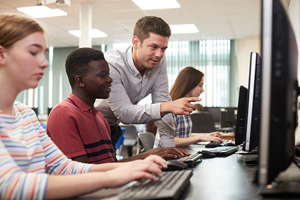 teacher helps a student who is working on a computer