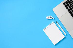 Laptop and office supplies on a blue background, suggesting a workspace or productivity theme