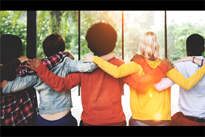 diverse group of five people with arms around each others' shoulders