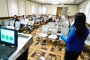 speaker in a blue jacket stands in front of an audience