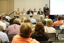 Photo taken from the audience's perspective looking at a stage of panelists.