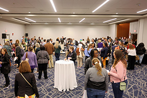 People standing and mingling at an indoor event in a conference hall