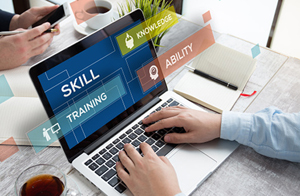 laptop with the words "skill, training, knowledge, and ability" displayed