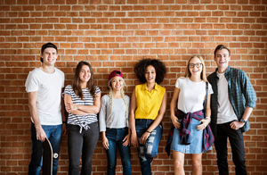 group of young people smiling in front of a brick wall