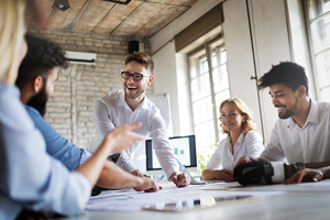 five smiling people sitting around a meeting table