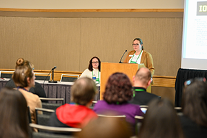 Two speakers presenting in front of an audience.