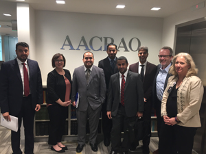 group dressed in business attire pose for a photo outside the AACRAO elevator entrance