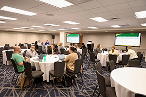 Training session in a classroom with attendees seated at tables facing a screen with slides