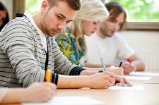 Male student glances at his peer's paper while others are taking an exam.