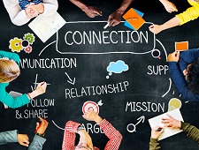 Group of people studying and writing while encircling a blackboard with the following words written in chalk: connection, communication, relationship, mission, follow & share, etc...