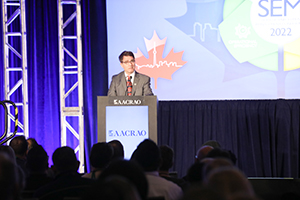 Photograph of outgoing SEM Conference director Clayton Smith speaking in front of an audience.
