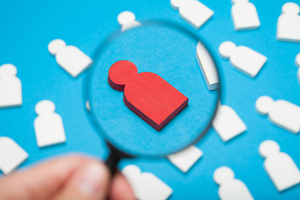 magnifying glass on an cut-out red figure surrounded by non-magnified white cut-outs
