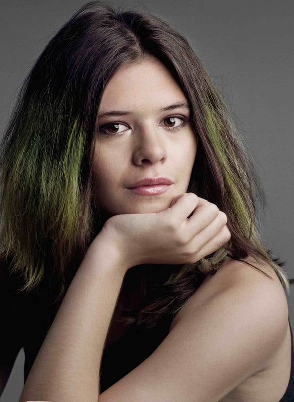 Portrait of a young woman resting her chin on her hand against a gray background