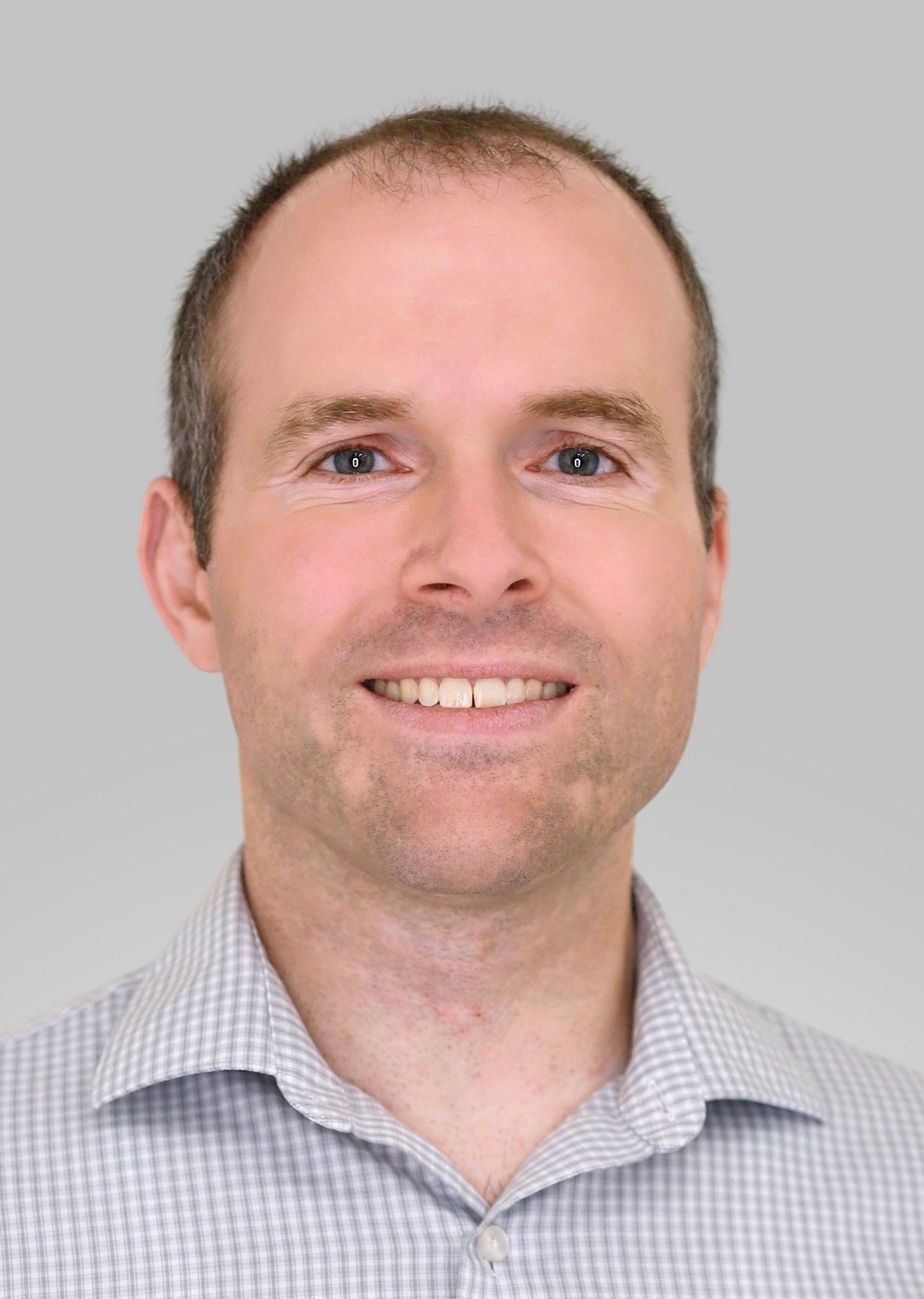 Smiling headshot of a man against a light gray background