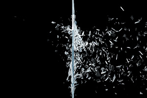 Photograph of a piece of glass breaking in to many shards.