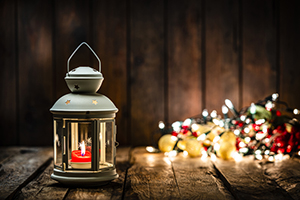 lantern with a red candle burning sits next to a pile of illuminated electric Christmas lights