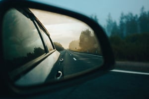 Road ahead seen through a car’s side mirror during a drive