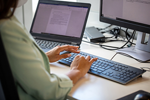 person in a green top types while at an office desk