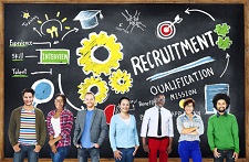 Group of people standing together in front of a giant blackboard with various symbols and words written in chalk on it.
