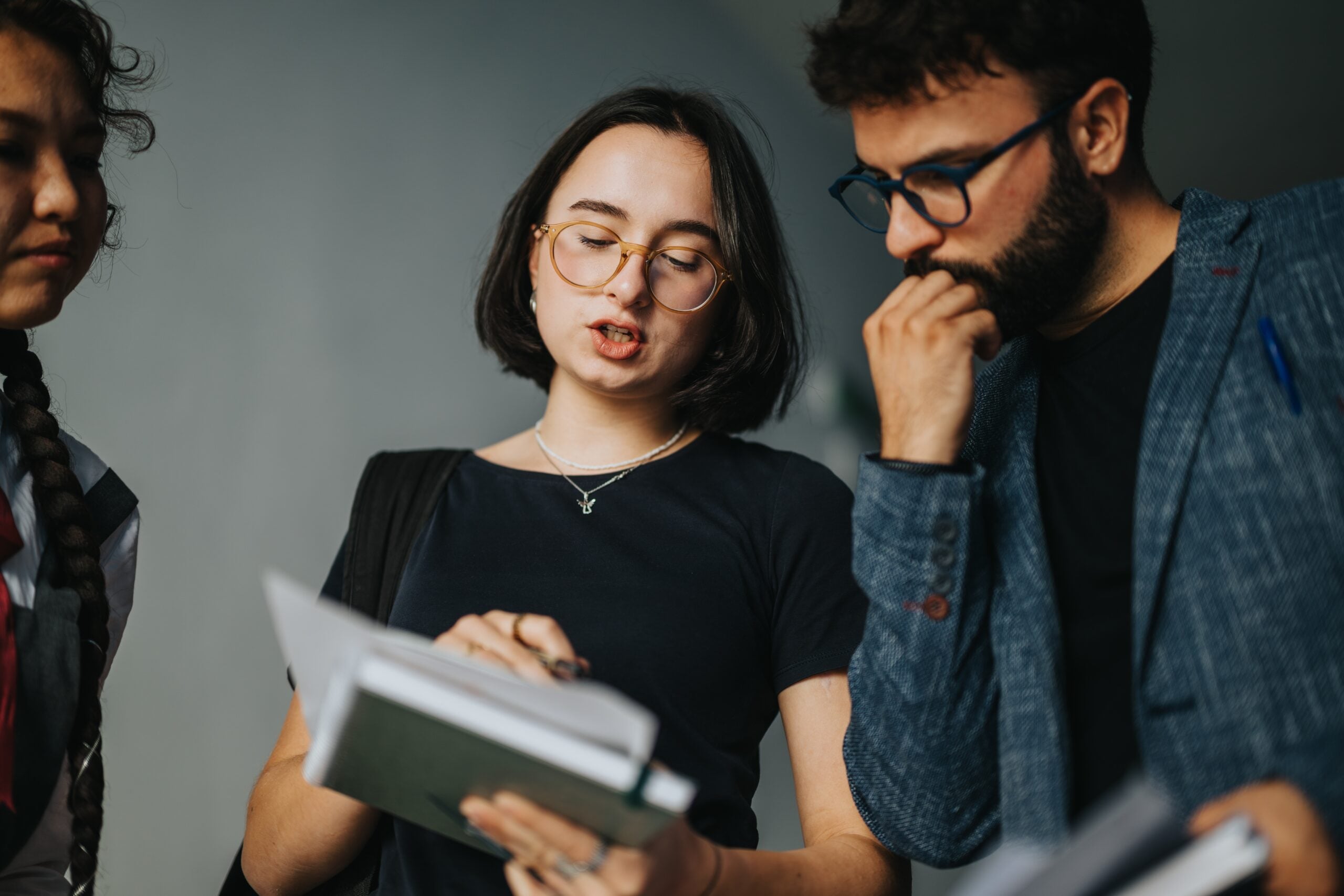 Three people reviewing documents together in a group discussion.