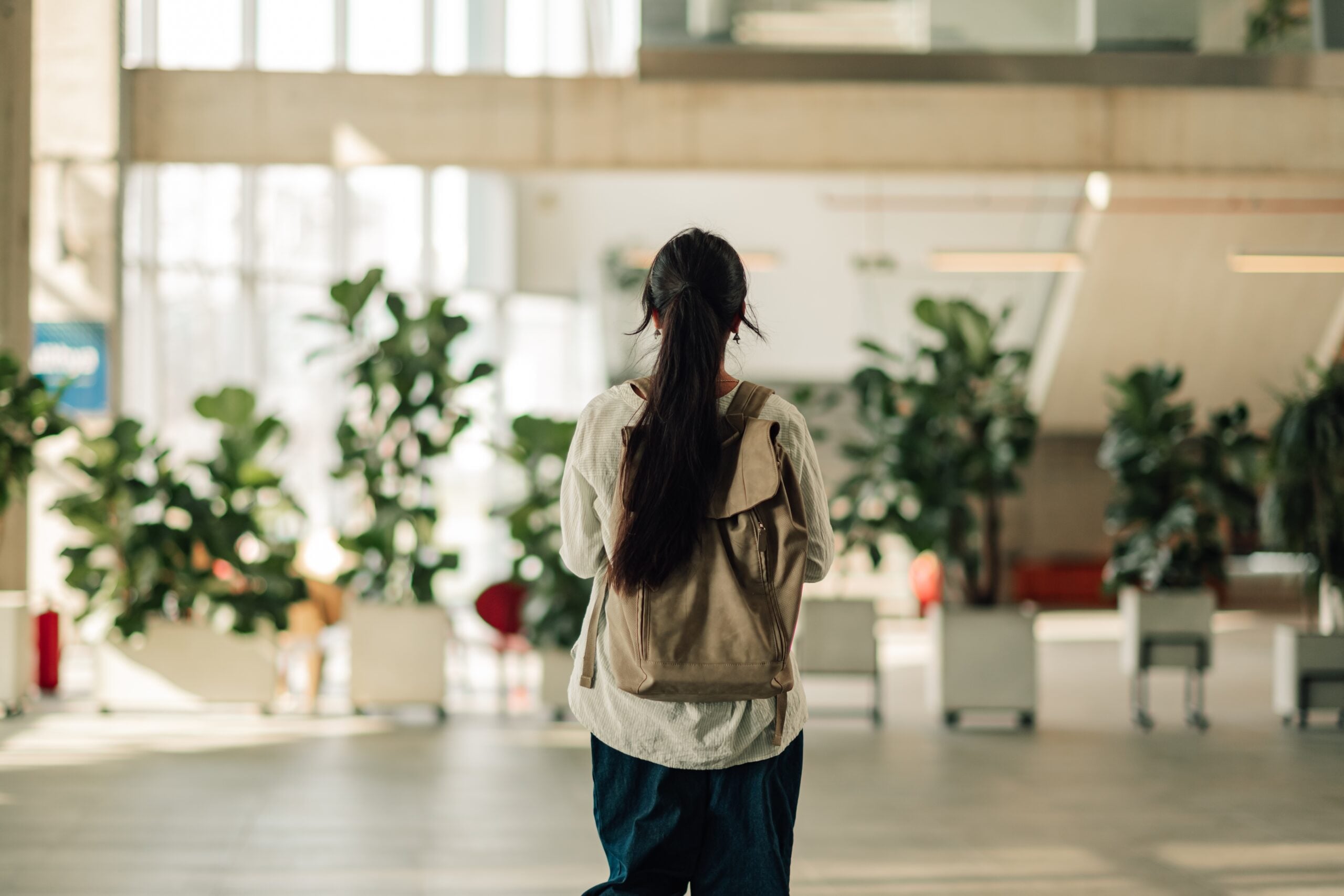 Claude responded: A student with a backpack walking through a bright campus building.A student with a backpack walking through a bright campus building.