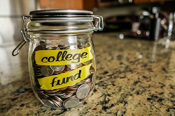Glass jar of change labelled "college fund" sitting on a kitchen countertop.